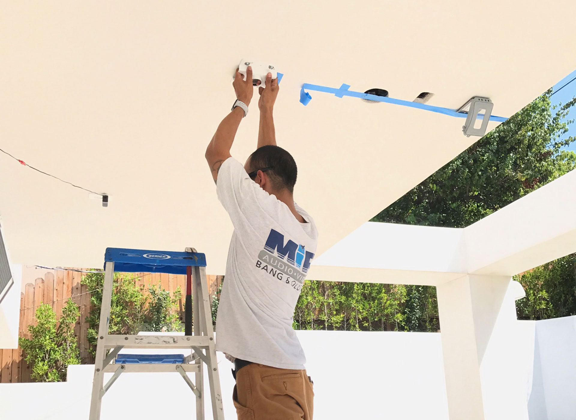 A MIR Audio Video technician installing a CCTV camera on a home patio ceiling