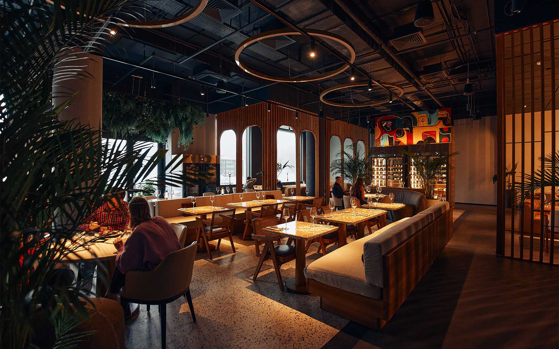 Dimly lit and elegantly decorated restaurant with rich table settings, with exposed restaurant speaker installation in the ceiling for a muted industrial look