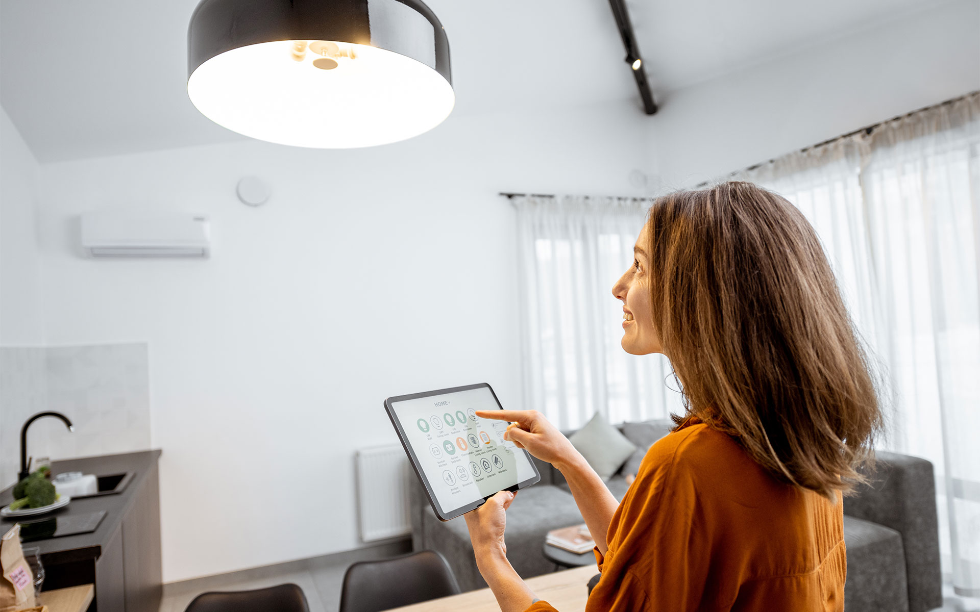 A young woman controlling her home lights with a digital tablet in the living room