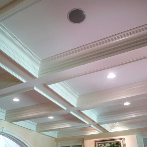 A beautiful white coffered ceiling with an in-ceiling speaker for the audio distribution system