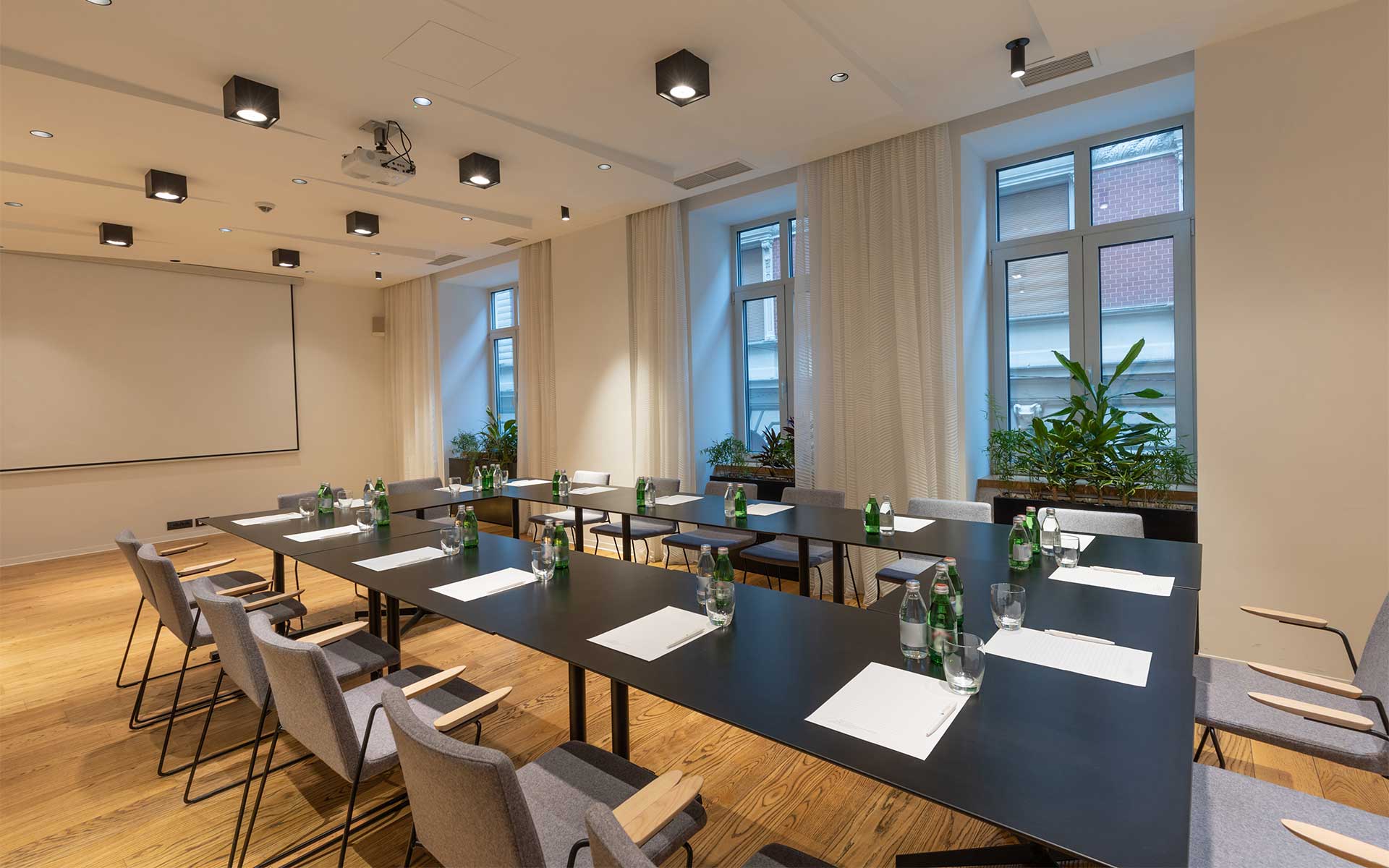 A modern conference room with a large screen projector and customized ceiling lights