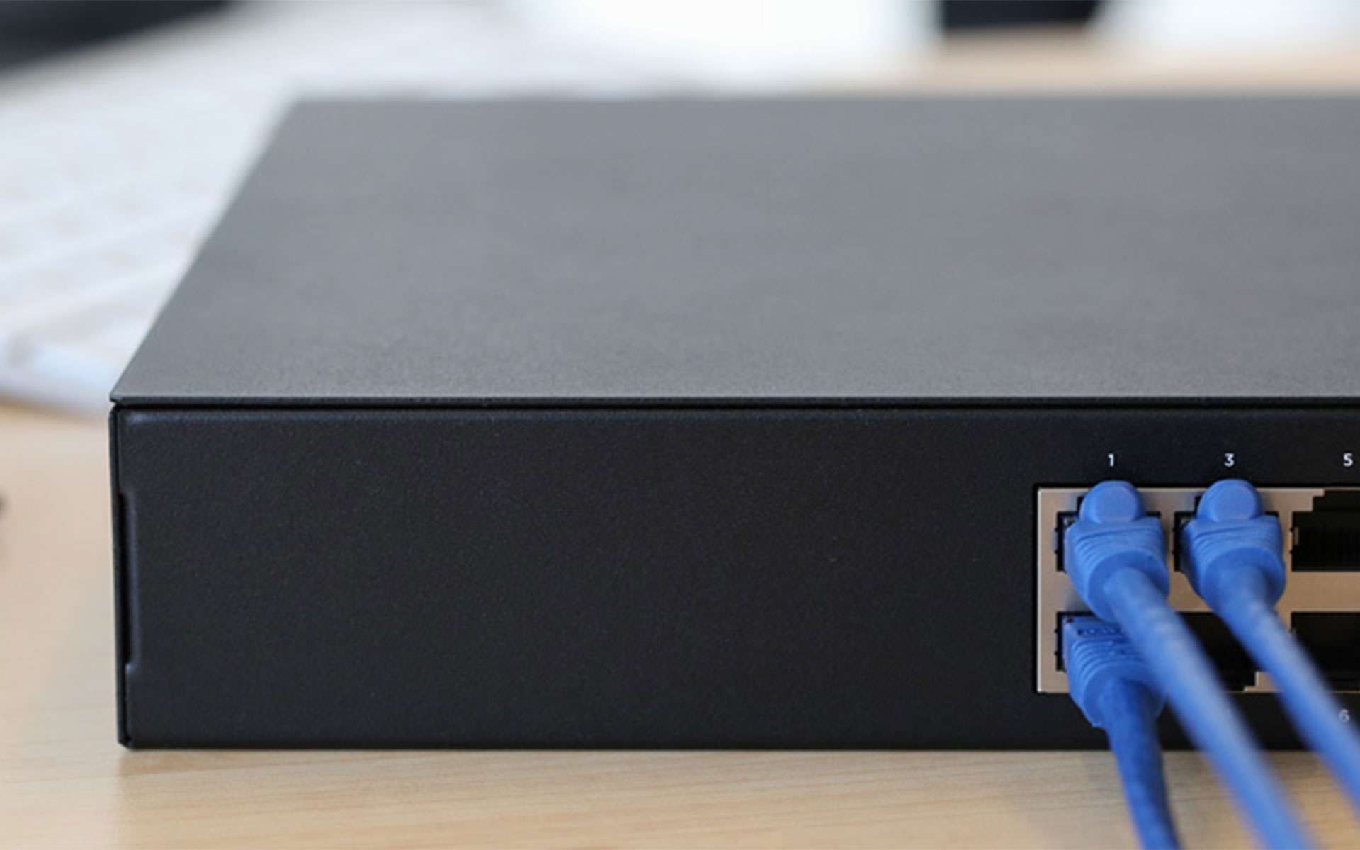 Close-up image of a black router box with three blue Ethernet cables plugged in