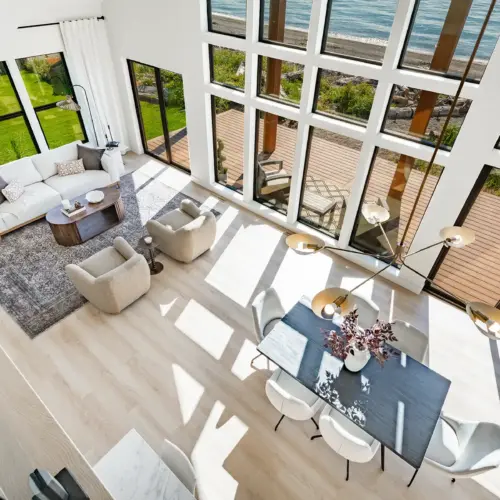 A spacious interior living room with floor-to-ceiling windows in a seaside estate with a Pacific Ocean view