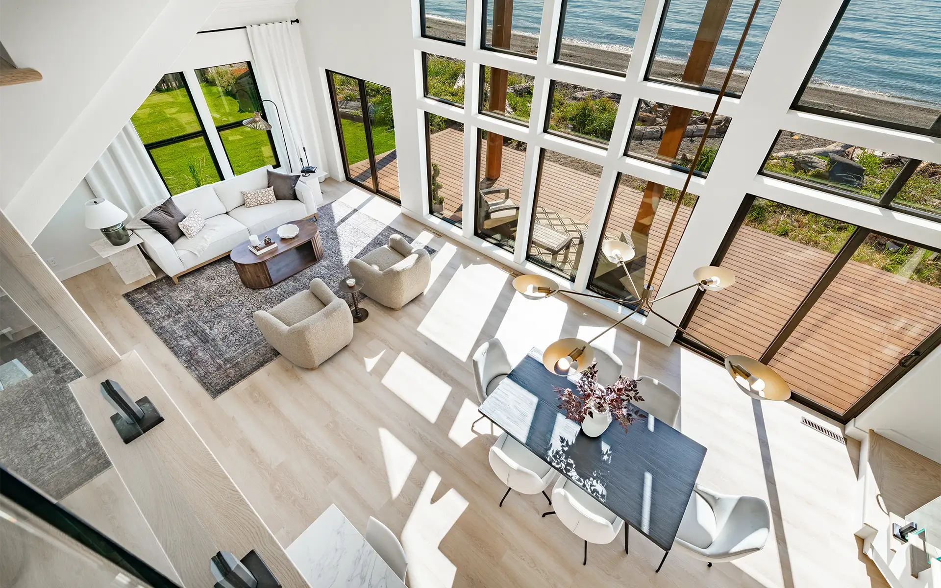 A spacious interior living room with floor-to-ceiling windows in a seaside estate with a Pacific Ocean view