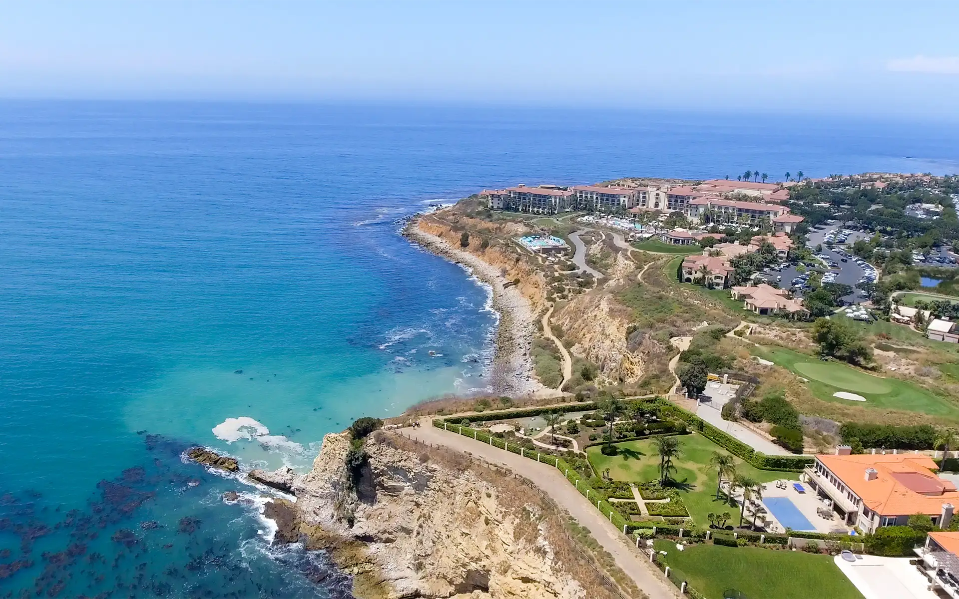 An aerial view of the Rancho Palos Verdes coastline in California, lined with homes, buildings, and greenspace