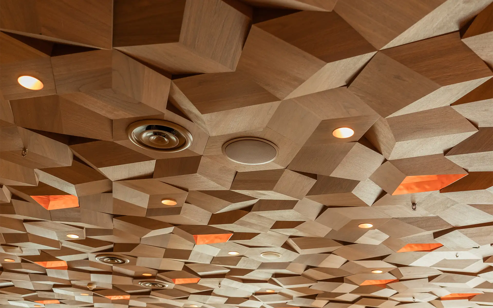 An intricate, textured wood-paneled ceiling with hidden speakers and vents